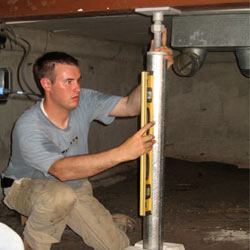 A contractor in New Windsor installing a crawl space jack post.