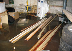 A severely flooding basement in New City, with lumber and personal items floating in a foot of water
