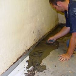 A basement waterproofer installing a perimeter drain system in Pearl River