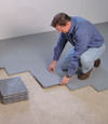 Contractors installing basement subfloor tiles and matting on a concrete basement floor in Kingston, New York