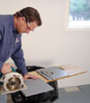 installing a waterproof vapor barrier on a basement floor to prepare for basement carpeting in a Spring Valley home
