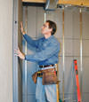 Insulated basement wall panels being placed against a concrete foundation wall in Monsey